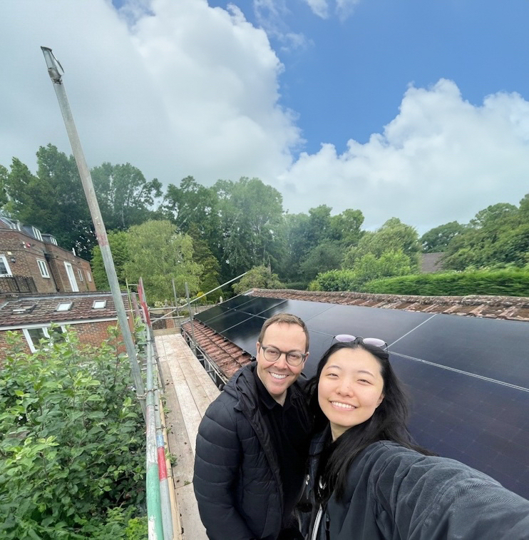 A selfie of two people next to newly installed solar array